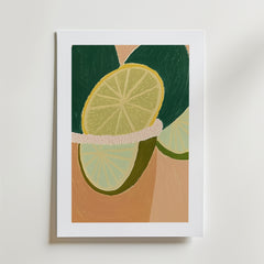 Bozetto Citrus Dream Poster visar två limeskivor med gröna skal på en beige bakgrund, presenterad i en vit matt ram och tryckt på premiumpapper med en lyxig matt finish.