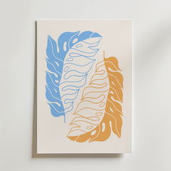 Golden Blue Leaves Poster från Bozetto har en minimalistisk, naturinspirerad design med två stora överlappande abstrakta löv - ett blått och ett orange - mot en ljusbeige bakgrund med flytande linjer och organiska former.