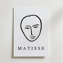 Minimal Matisse Poster by Bozetto har ett minimalistiskt svart linjeansikte på en vit bakgrund med fet "MATISSE" text, tryckt på premiumpapper med en matt finish för en elegant look.
