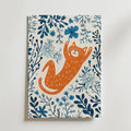 No-9 features an illustration of an orange cat playfully reaching for a blue flower, with blue and teal leaves and flowers on a white background.