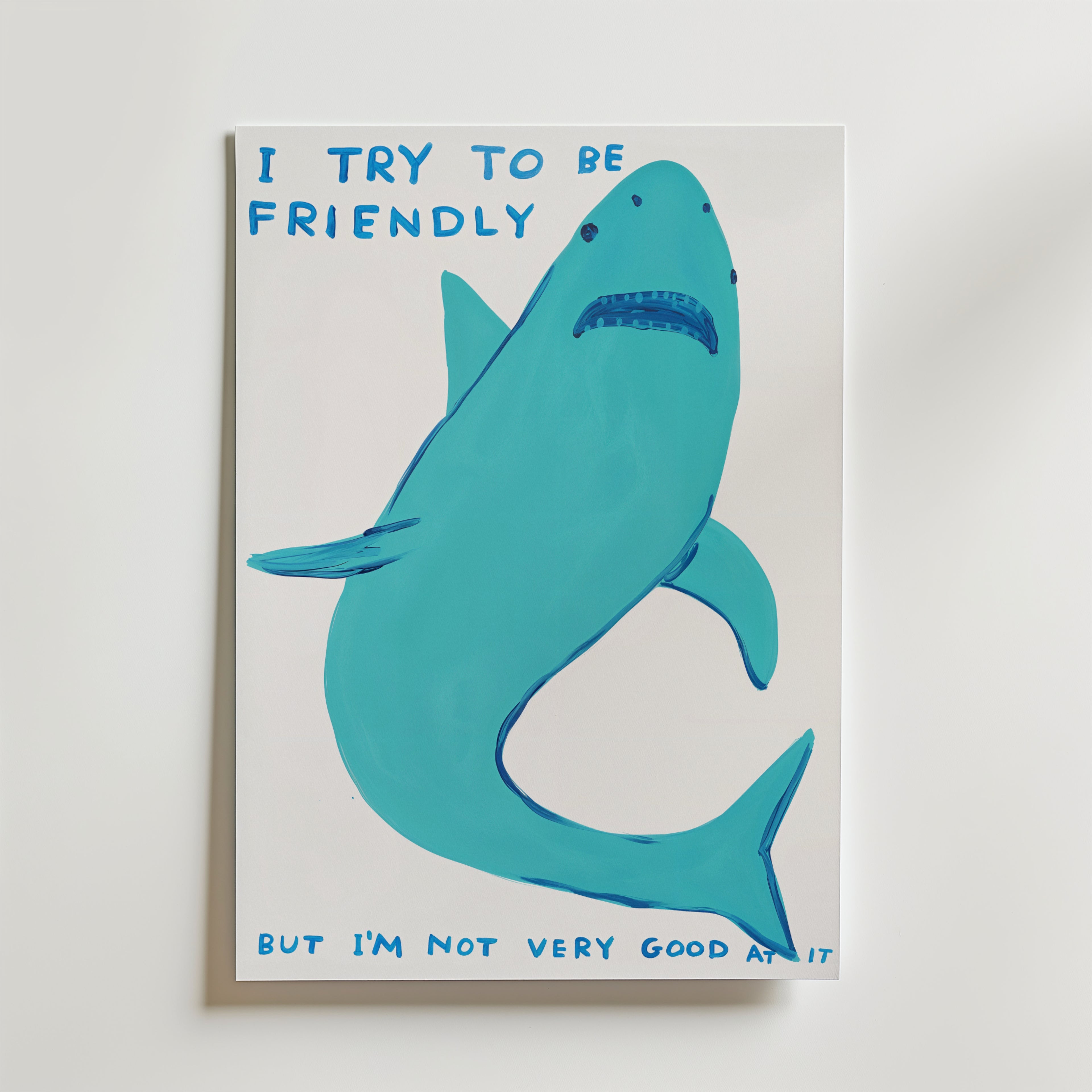 Bozetto Friendly Shark Poster visar en blå haj med ett sorgset ansikte och texten "I try to be friendly but I'm not very good at it" i blå bokstäver mot en vit bakgrund.