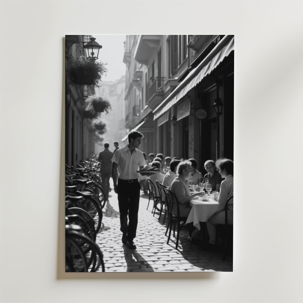 Charming Street Café Poster från Bozetto visar en svartvit scen av ett livligt utomhuscafé med gäster, en servitör och cyklar på en kullerstensgata - perfekt att visa på premiumpapper.