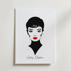 Den tidlösa Audrey Hepburn Postern från Bozetto har en minimalistisk svartvit design av Audrey med kort hår, djärv eyeliner och röda läppar på matt papper. "Audrey Hepburn" är elegant skrivet under och skapar en klassisk, tidlös look.