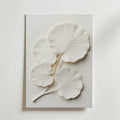 Bozetto Ginkgo Leaf Textured No.2 Poster har fyra överlappande vita blad med detaljerade ådror, upphöjda mot en slät bakgrund, vilket skapar en minimalistisk och elegant 3D-effekt för ditt rum.