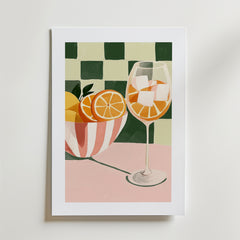 Bozetto's Tropical Charm Drink Poster föreställer en skål med apelsinskivor, ett vinglas med apelsinskivor och is, på en rosa med grönvitrutig bakgrund, tryckt på FSC-certifierat premiumpapper.