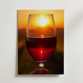 En hand håller ett glas rött vin framför en glödande solnedgång på Bozetto Sunset Sip Poster. Solen svävar ovanför kanten med en mjukt suddig bakgrund som framkallar värme och elegans på premiumpapper.