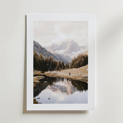 Mountain Lake Reflection Poster by Bozetto är ett kvadratiskt fototryck av en lugn bergsscen med en reflekterande sjö och tallar, med två små figurer, på FSC-certifierat premiumpapper med en lyxigt matt yta, mot en vit bakgrund.