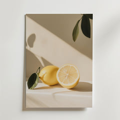 Ett minimalistiskt foto av en hel och en halv citron med ett grönt blad, mjuka skuggor och en neutral bakgrund i Golden Simplicity Poster från Bozetto, tryckt på premiumpapper för en lyxig matt finish.