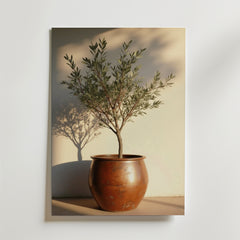 Postern "Potted olive tree in rustic terracotta" från Bozetto föreställer ett litet olivträd i en rund terrakottakruka, mjukt skuggad på en krämfärgad vägg. Tryckt på FSC-certifierat premiumpapper för en lugn, minimalistisk stil.