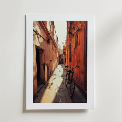 Moroccan Alley Poster" av Bozetto föreställer en smal solbelyst gränd med orangefärgade väggar och en cykel, tryckt på FSC-certifierat premiumpapper med matt yta för en högkvalitativ finish.