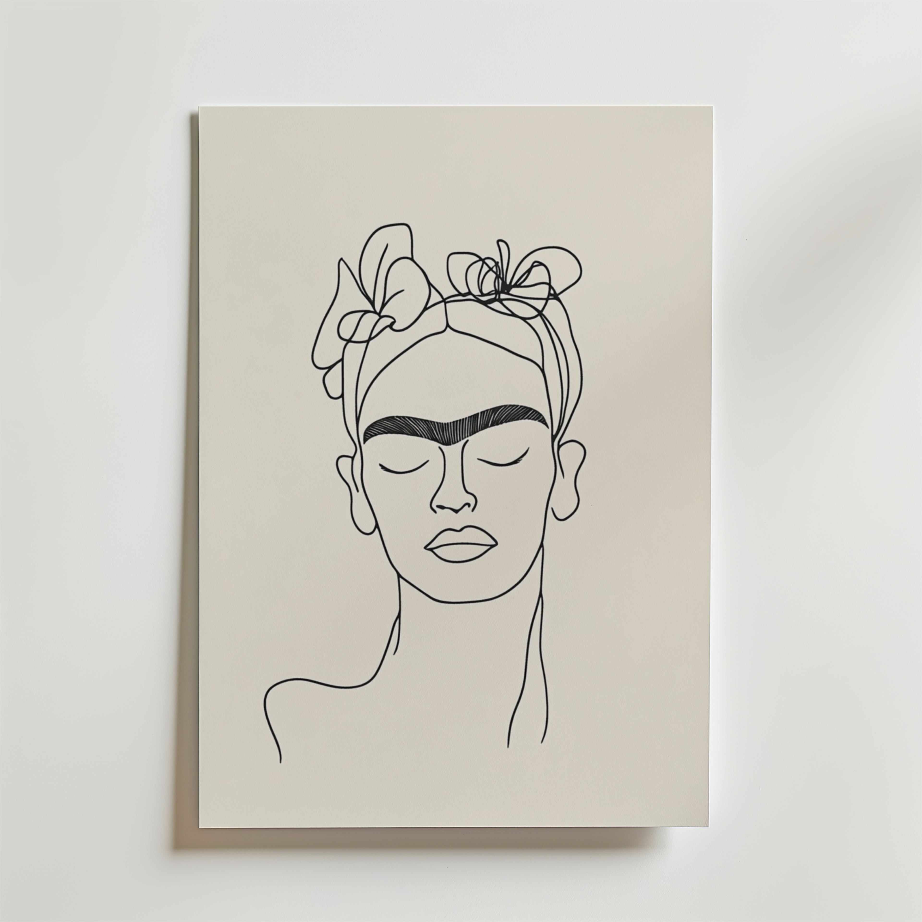 Bozetto Frida Inspired Line Art No.2 Poster föreställer en kvinna med blommor i håret och djärva ögonbryn, ritad på cremefärgat premiumpapper mot en ljus bakgrund.