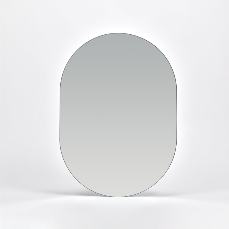 Bozetto Spegel Ark 50x70 cm, en stor ramlös väggspegel med en platt bas, är monterad på en vit vägg och reflekterar en mjuk neutral gradient.