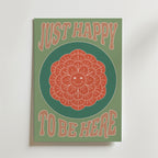 Just Happy Flower Poster by Bozetto föreställer en leende orange blomma som utstrålar enkel glädje, omgiven av grönt, med fet beige text ovanför och under: BARA GLAD ATT VARA HÄR.