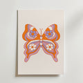 Orange Butterfly Symmetry Poster från Bozetto föreställer en retroinspirerad fjäril med orange, rosa och lila blommiga vingar på en vit bakgrund - ett perfekt och stilfullt tillägg till alla barnrum.