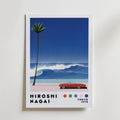 Hiroshi Nagai Crimson Wave Poster by Bozetto föreställer en röd cabriolet vid havet, en palm och en blå våg. "Hiroshi Nagai", färgprickar och "Tokyo 1973" visas nedan, allt mot en klar gradientblå himmel.