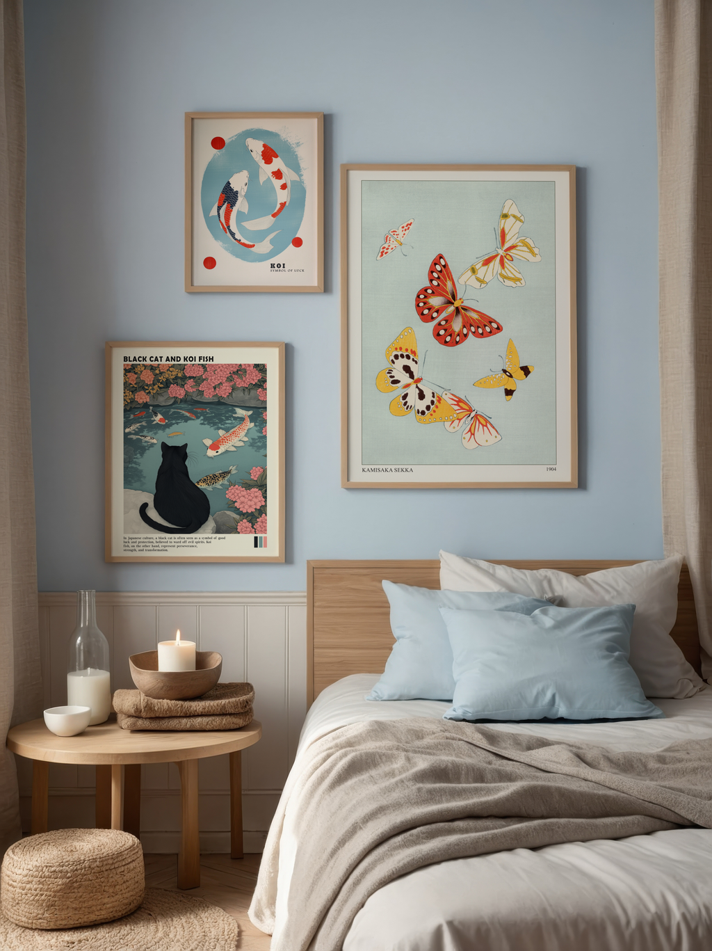 Ett mysigt sovrum med ljusblå väggar har Bozetto Bundle 3-pack Japandi No. 3 konsttryck - koifiskar, fjärilar och en svart katt - som skapar en unik konstvägg ovanför sängen. På nattduksbordet i trä står en glaskaraff, stearinljus och en vas.