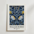 William Morris Blue Flowers Poster by Bozetto har ett symmetriskt blommönster i blå toner med subtila gyllene accenter, vita kanter och inkluderar konstnärens namn och titel nedan.