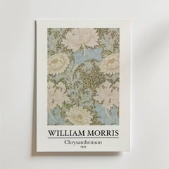 Bozetto William Morris Chrysanthemum Poster visar den intrikata blomsterdesignen från 1876 i mjukt grönt, krämfärgat och blått på en himmelsblå bakgrund med texten "WILLIAM MORRIS Chrysanthemum 1876" under bilden.