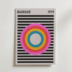 Bozetto Bauhaus Spectrum No. 2 Poster visar BAUHAUS 1919 högst upp, djärva horisontella svarta linjer och ett slående centralt mål i rosa, orange, gult och blått på en skarp vit bakgrund.