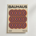 Bozetto Bauhaus Echo Poster har en fet svart "BAUHAUS" text, färgglada koncentriska halvcirklar som bildar en geometrisk design i mitten och "POSTER AUGUST 1923" längst ner på en beige bakgrund.