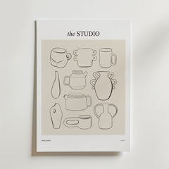 Postern Clay And Character Poster från Bozetto har minimalistiska svarta linjeteckningar av abstrakt keramik och vaser på en beige bakgrund, vilket ger kreativ inredning till alla rum. Postern visas uppställd mot en vit vägg.